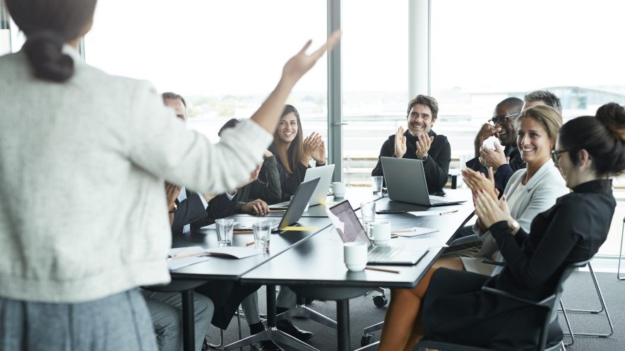 Üzletemberek a örülnek egy tapsolnak egy modern tárgyalóteremben